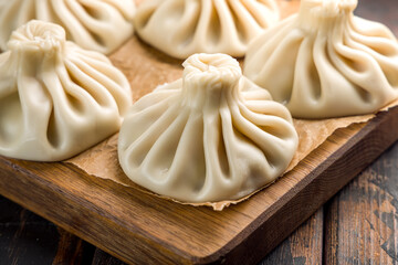 Khinkali with lamb on wooden board on dark wooden table macro close up