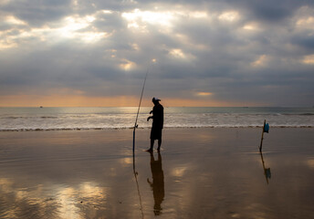 Man fishing in Asia at sunset on beach
