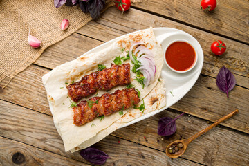 Lamb Lula kebab with red onion and tomato sauce top view on wooden table