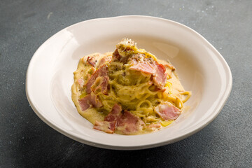 Spaghetti Carbonara with bacon on grey concrete table