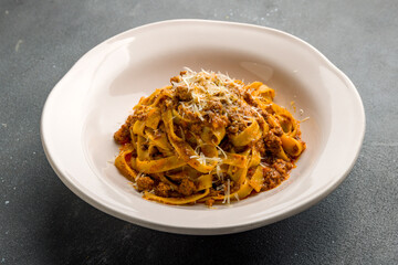Pasta fettuccine Bolognese on plate on grey concrete table