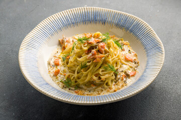 tagliatelli pasta with salmon and creamy sauce on grey concrete table