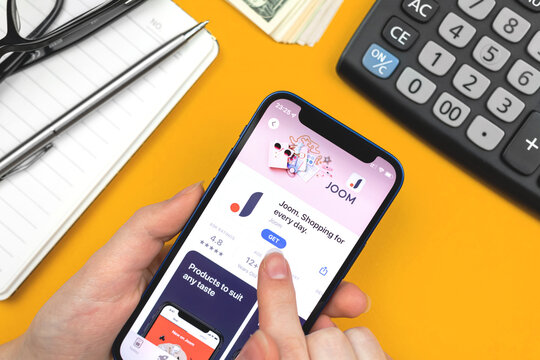 Joom app icon close-up. Woman uses the application on Apple iPhone 12