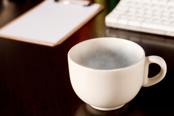 cup of green tea, with hot steam, on the work desk.