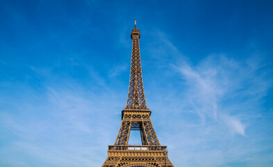 Paris Eiffel Tower and bright blue sky in Paris, France. Eiffel Tower is one of the most iconic landmarks of Paris. Copy space for your text.