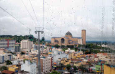 rain water on a glass cable car window with a panoramic view of the city of Aparecida do Norte, Brazil.