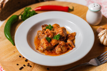 baked meat in slices in tomato red sauce in a white plate