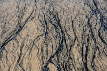 unusual pattern of mixing yellow and black sand on the beach at low tide 