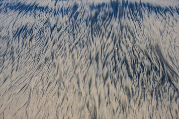 unusual pattern of mixing yellow and black sand on the beach at low tide 