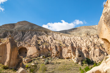 Fototapeta premium Fairy chimneys in Cappadocia Valley, Zelve Open Air Museum Turkey. Mushroom-shaped volcanic rocks known as fairy chimneys in Cappadocia. Ancient churches and houses carved into the rocks.