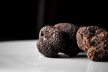Freshly picked organic black truffle, ready to serve in a restaurant with black background. Tuber nigrum