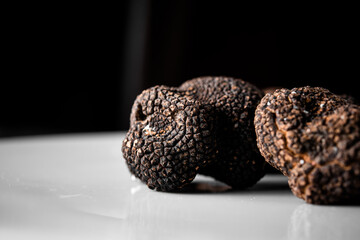 Fototapeta premium Freshly picked organic black truffle, ready to serve in a restaurant with black background. Tuber nigrum