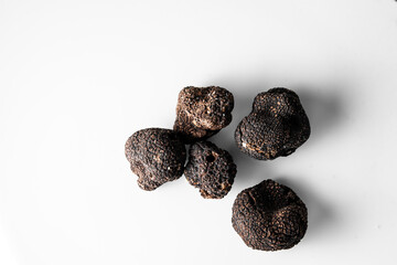 several freshly picked organic black truffles on a white background ready to serve. Tuber nigrum in a restaurant.