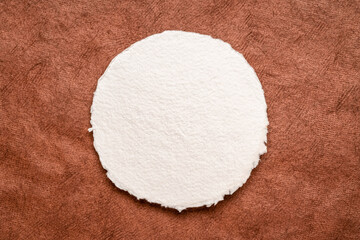 circular sheet of blank white watercolor paper against textured handmade bark paper