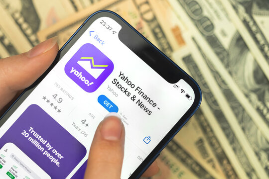 Yahoo Finance app icon close-up. Woman with application on Apple iPhone 12