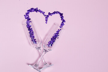 Champagne glass with purple sequins scattered in the form of heart. Valentine's Day design and free space