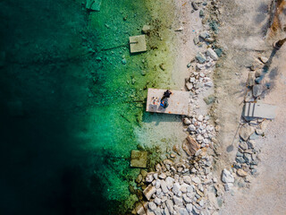Two people eating breakfast, camping right at the ocean in Split, Croatia at Kasjuni Beach. Aerial drone view.