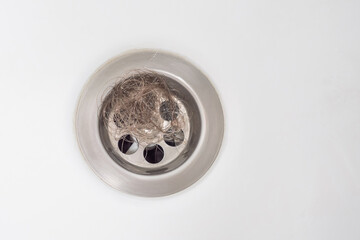 Top view. Clogging of the drain due to loose hair. A bundle of hair is obstructing the sink drain....