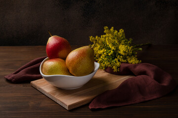 Still life with pears and a branch of a solidago flower. Close-up, horizontal orientation, low key.