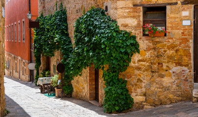 Fototapeta premium View of old cozy street in medieval town. Architecture and landmark of Italy. The picturesque narrow street and the ancient architecture of San Gimignano, Tuscany, Italy.