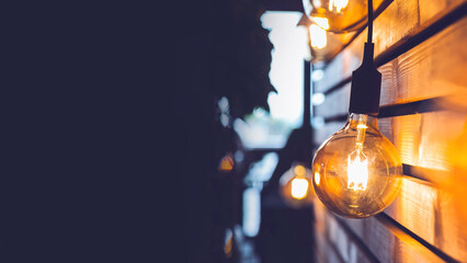 Lightbulb hanging down on wooden slatted wall. event invite.
