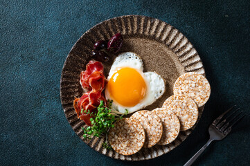 Breakfast on Valentine's Day - fried eggs in the shape of a heart and olives. Healthy breakfast. Rice cakes with eggs and hamon. Romantic breakfast. Top view.