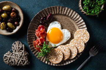Breakfast on Valentine's Day - fried eggs in the shape of a heart and olives. Healthy breakfast. Rice cakes with eggs and hamon. Romantic breakfast. Top view.