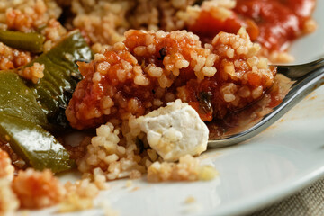 Green bell pepper stuffed with bulgur and vegetables, served with tomato sauce.