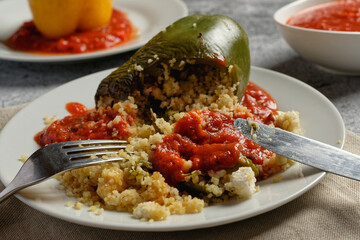 Green bell pepper stuffed with bulgur and vegetables, served with tomato sauce.