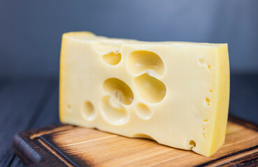piece of cheese with big holes Maasdamer wooden board