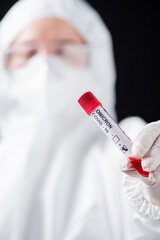 close up view of positive covid-19 omicron variant test in hand of blurred doctor in hazmat suit...
