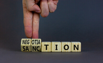 Sanction or negotiation symbol. Businessman turns cubes, changes the word sanction to negotiation....