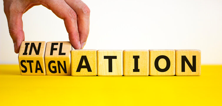 Inflation and stagnation symbol. Businessman turns cubes, changes the word inflation to stagnation. Beautiful yellow table, white background, copy space. Business, inflation and stagnation concept.