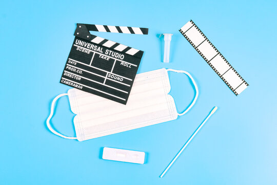 Paper Movie Clapperboard, Film Strip, Medical Mask And Coronavirus Test On A Blue.