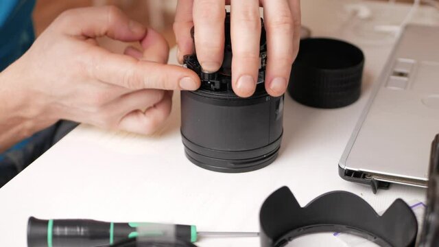 man repairs camera lens, autofocus motor, tools. Workshop, master