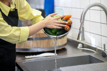 Woman in the kitchen washing vegetables before cooking