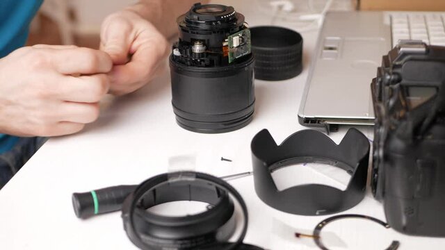 man repairs camera lens, autofocus motor, tools. destroyed, broken, not working