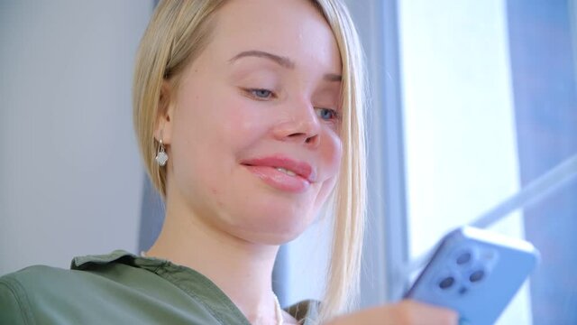 Woman with prosthetic one eye communicating online with mobile phone. Beautiful one-eyed female using smartphone with smile. Female abuse survivor smiling. 4k video of violence against women concept