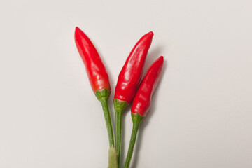 three small chili peppers on white background