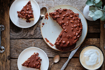 Chocolate Cake. Sponge cake and tender soufflé, creamy mousse. Garnished with milk chocolate and peanut. Top view, horizontal,  wooden background and coffee.