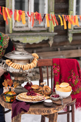 Festive decor for Maslenitsa on the table: pancakes, bagels, a samovar. Russian folk traditions. Shrovetide concept.