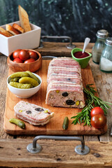 Terrine with pistachios and olives. Side view. Tomatoes, pickles, rosemary.