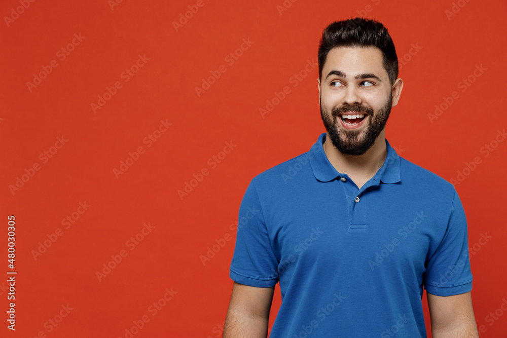 Canvas Prints Young smiling amazed cheerful fun happy caucasian man 20s wear basic blue t-shirt looking aside on workspace area mock up isolated on plain orange background studio portrait. People lifestyle concept.