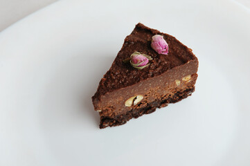 Slice of vegan chocolate nut cake on white plate close-up