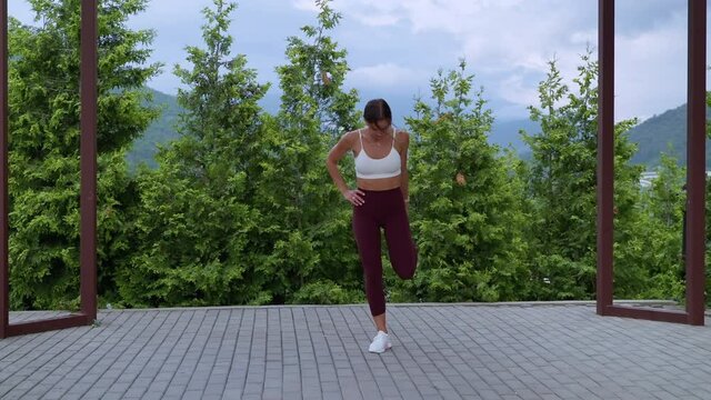 Athletic girl doing standing quad stretch on outdoor training