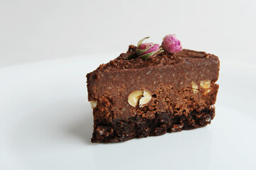 Slice of vegan chocolate nut cake on white plate close-up