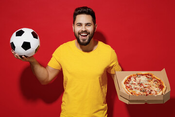 Cheerful fun young bearded man football fan in yellow t-shirt cheer up support favorite team hold...