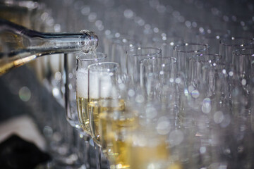 Champagne pouring in glasses from a bottle. Splash and drops. Concept for holidays 