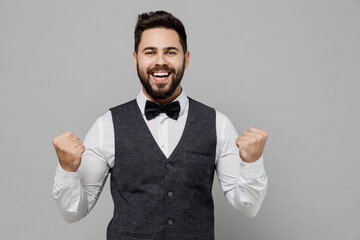 Young overjoyed barista male waiter butler man 20s wear white shirt vest elegant uniform work at cafe do winner gesture isolated on plain grey background studio portrait. Restaurant employee concept.