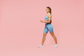 Fototapeta na wymiar Full body fun young strong sporty athletic fitness trainer instructor woman wear blue tracksuit spend time in home gym walk going isolated on pastel plain light pink background. Workout sport concept.
